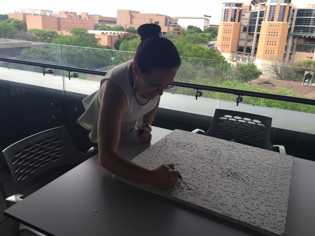 Leah signs a ceiling tile in a department tradition to celebrate her defense.